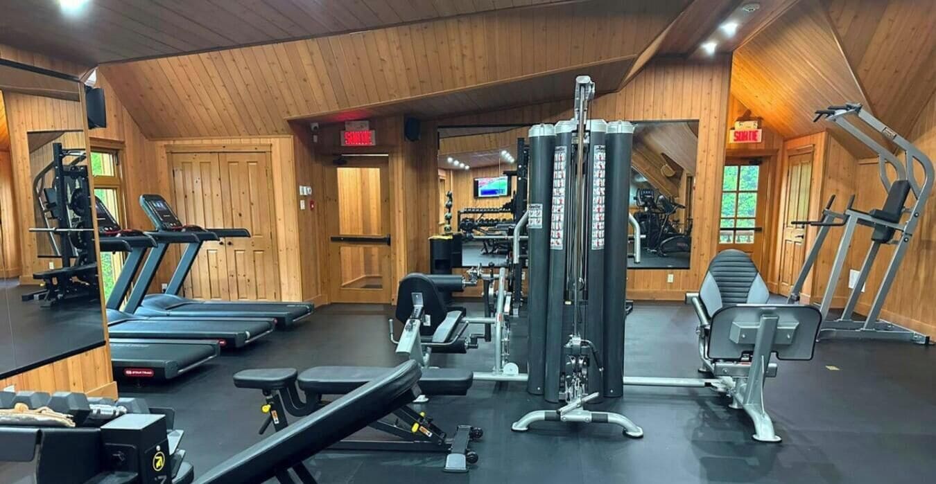Une salle de sport équipée de tapis de course, d’appareils de musculation et de poids libres.