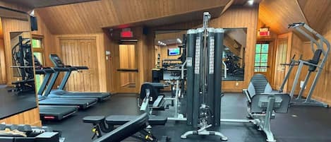 Un gimnasio con cintas de correr, máquinas de pesas y pesas sueltas.