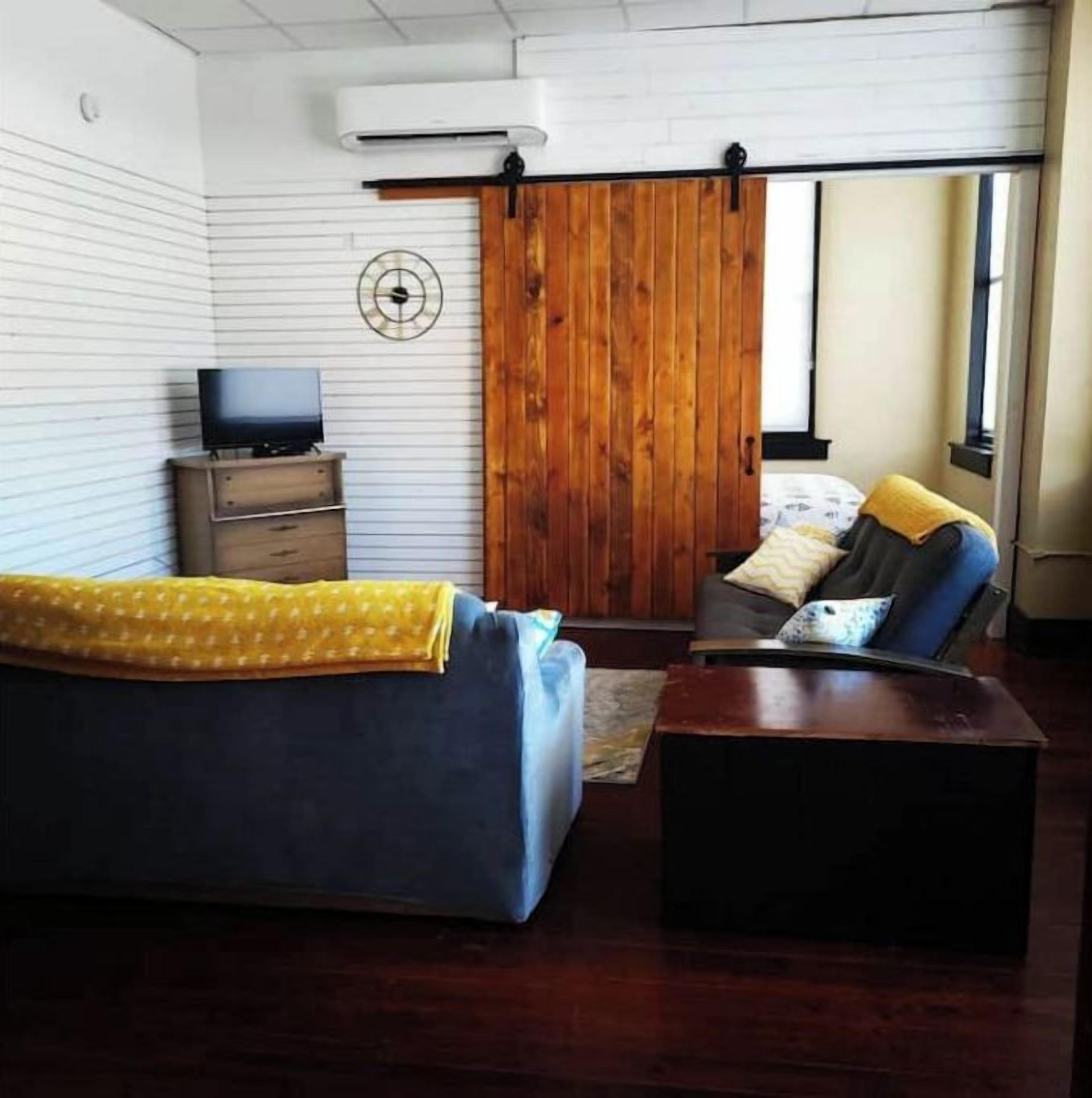 A room with a sofa, a small TV, a wooden sliding door, and a window.