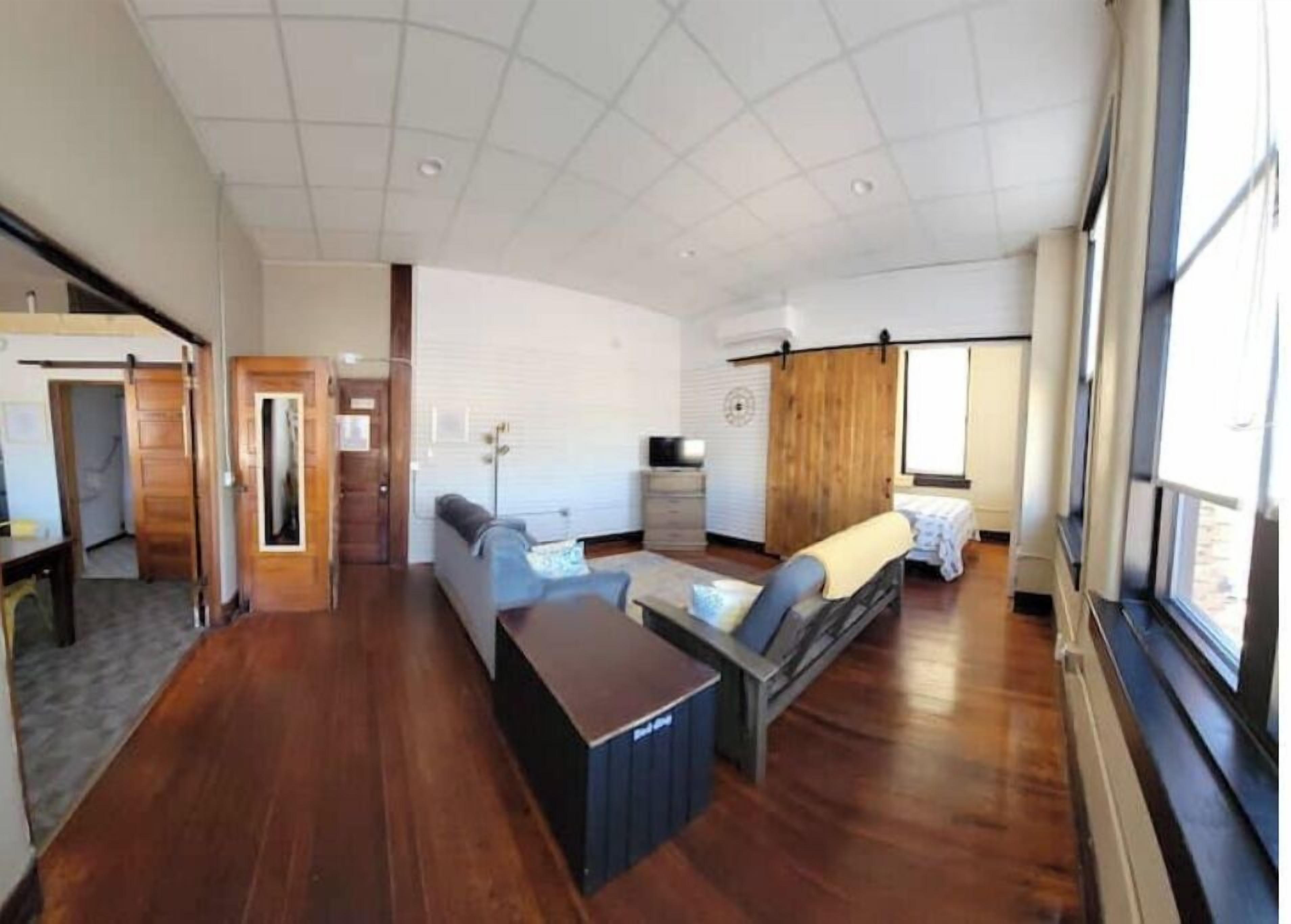 A spacious living area with a wooden floor, a sofa, a coffee table, and a TV.