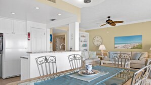 A spacious living area with a dining table, chairs, a sofa, and a ceiling fan. - Anna Maria Island Direct Beachfront Condo- Awesome View and Amazing Sunsets (Holmes Beach)