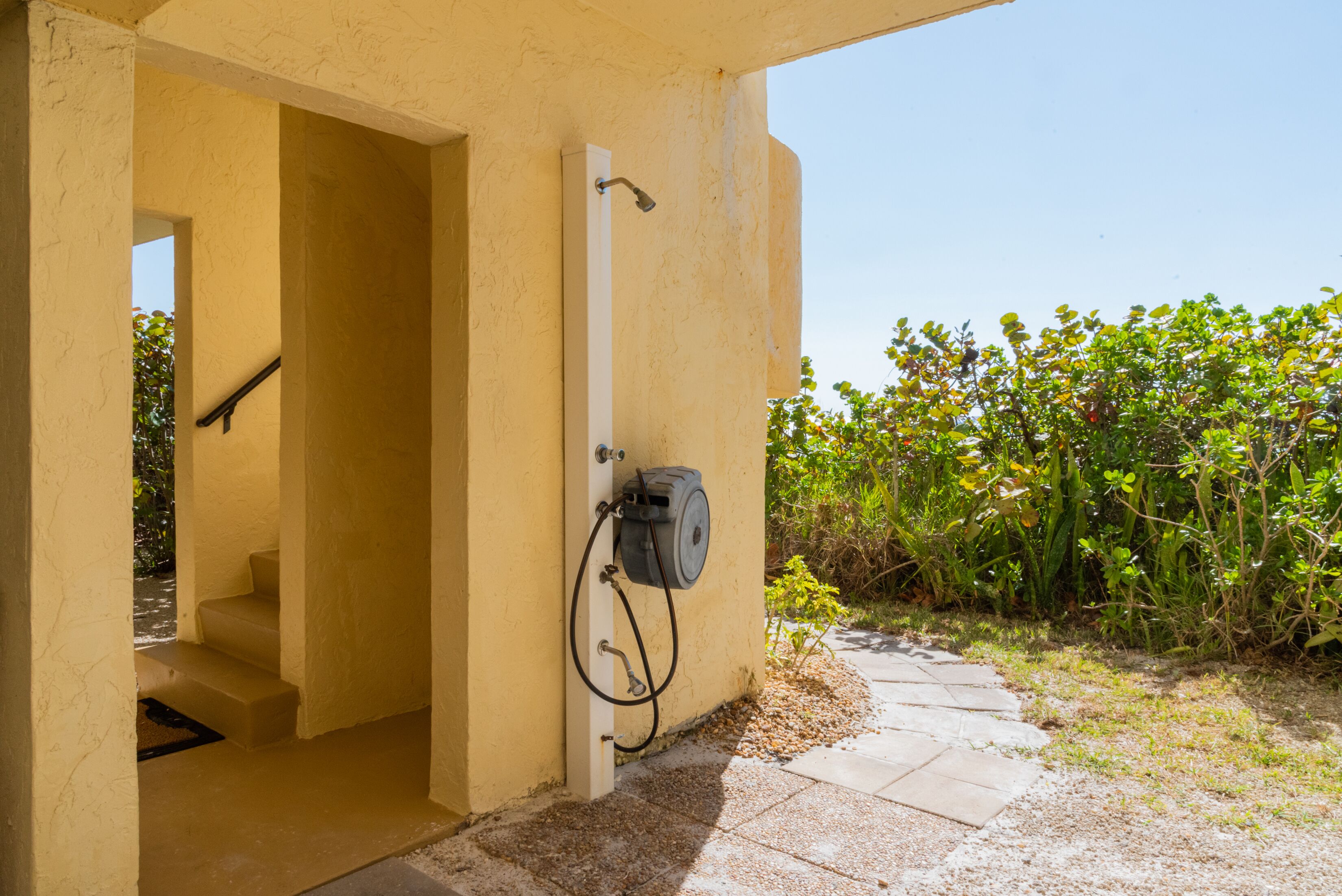 Une salle de bain avec une douche, un porte-serviettes et un petit marchepied menant à une porte.