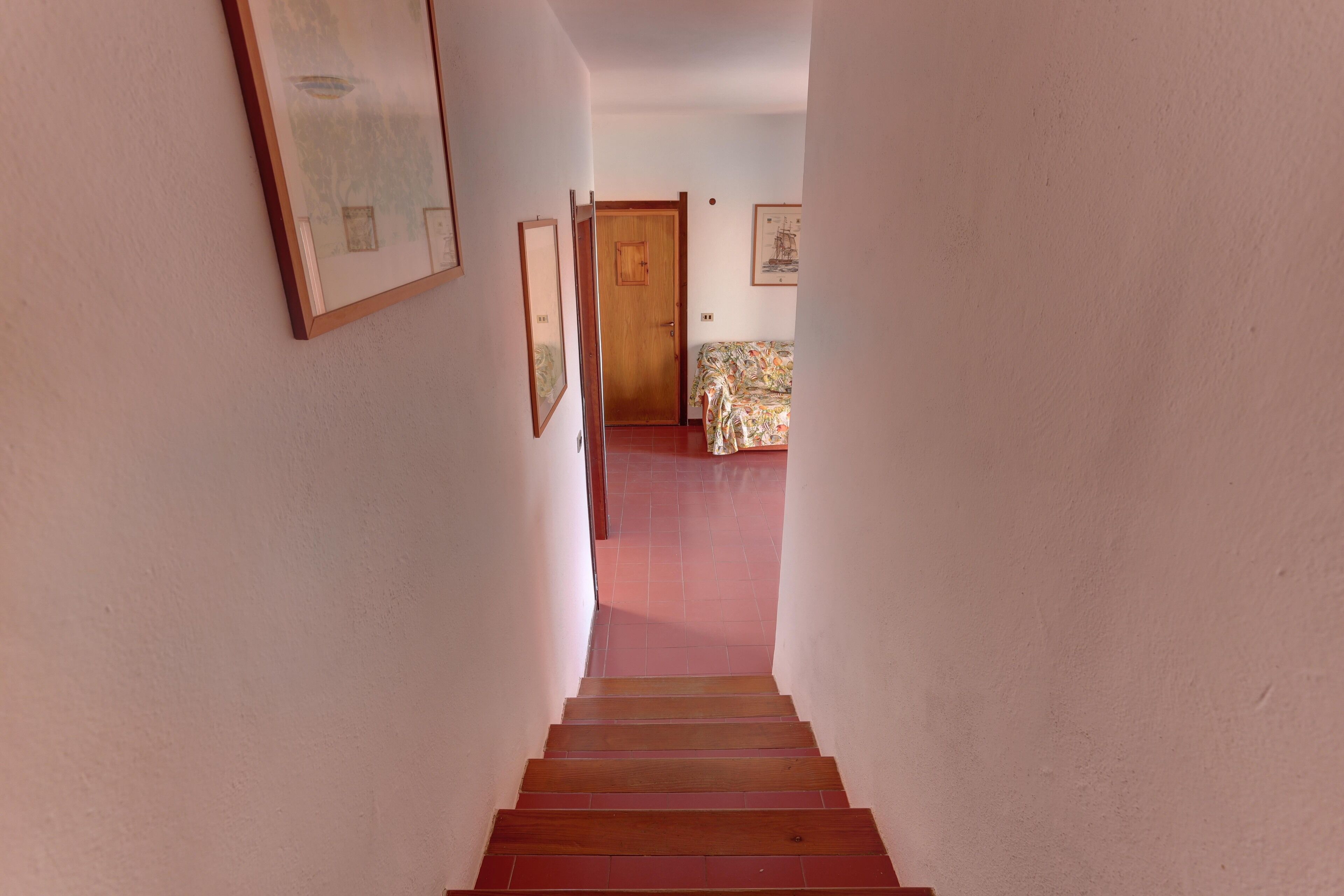 A narrow staircase leading to a room with a bed and a door.