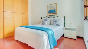 Une chambre à coucher avec un lit, une table de chevet, une armoire et un tableau au mur.
