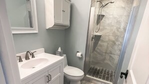 A bathroom with a shower, toilet, and sink.
