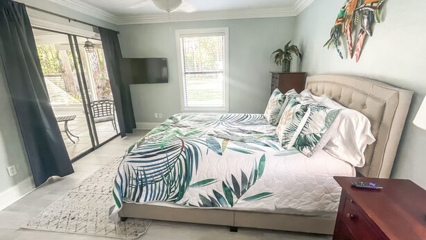 A bedroom with a bed, a ceiling fan, a window, and a view of the outdoors.
