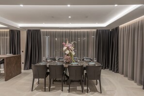 Een moderne eetkamer met een ronde tafel voor zes personen, omringd door donkere stoelen.