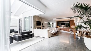 A spacious living area with a modern kitchen, a dining area, and a large plant.