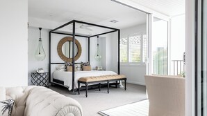 A bedroom with a four-poster bed, a round mirror, and a bench.