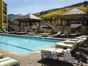 Relax by the pool surrounded by lounge chairs and sunbeds, with shaded seating areas nearby.
