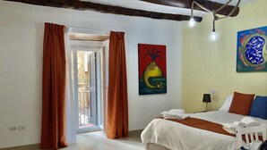A bedroom with a bed, a painting, and a view through an open door. - A Room de Scugnizzi (Naples)