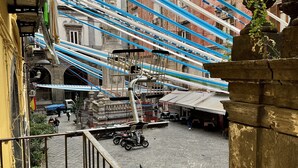 A courtyard with a stone floor, metal railing, and potted plants. - A Room de Scugnizzi (Naples)