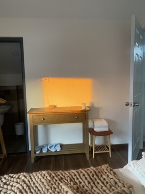 A bedroom with a wooden nightstand, a small stool with a towel, and a large, textured rug. - A Nordic Design Apartment,close to the center, well prepared&super friendly host (Thành phố Đà Lạt)