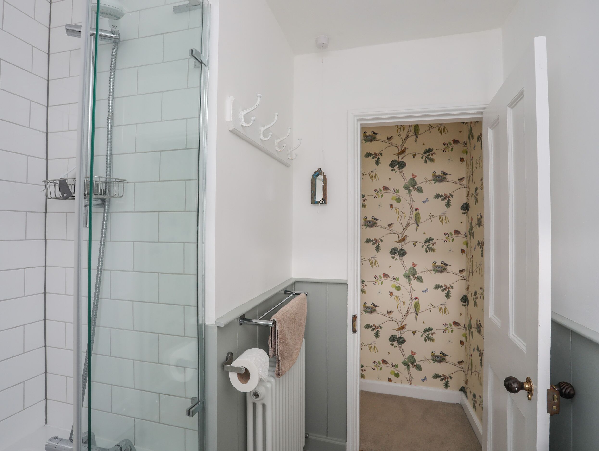 A bathroom with a glass shower enclosure, a towel rack, and a toilet paper holder.