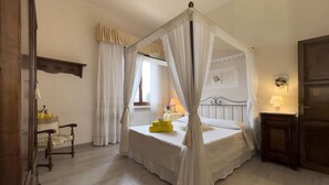 A bedroom with a four-poster bed, a bedside table with a lamp, and a chair. - Villa a Montaione ID 3114 (Iano)