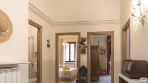 A hallway with a bed, a chair, a radiator, a television, and a door leading to another room. - Villa a Montaione ID 3114 (Iano)