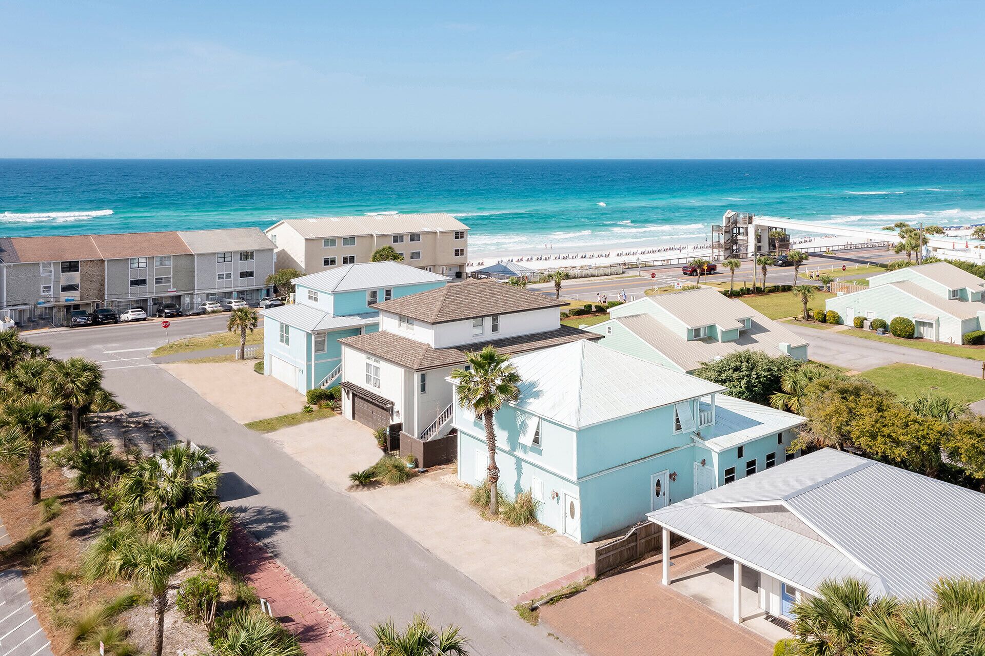 A coastal residential area with beachfront properties, including a multi-story building with a flat roof and a single-story building with a gabled roof.