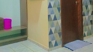 Habitació amb terra de rajola, una porta de fusta, un televisor fixat a la paret i una pared decorada amb un motiu.