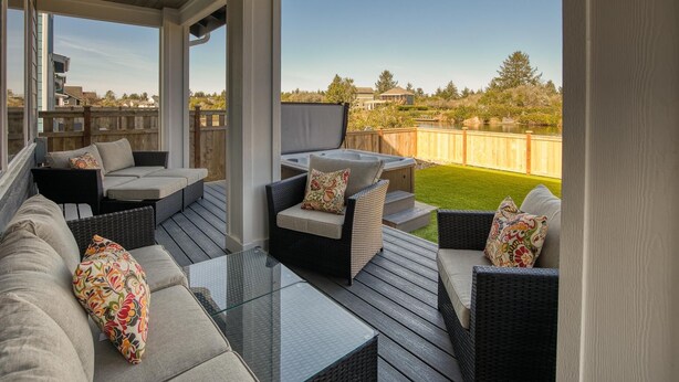 Eine überdachte Terrasse im Freien mit Korbmöbeln, einem Glastisch und einem Whirlpool.