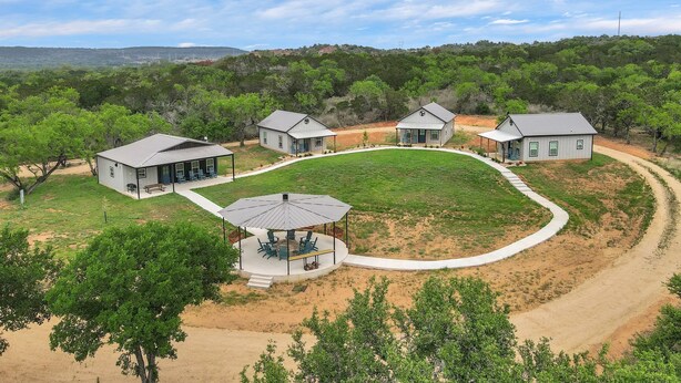 Un ensemble de maisons regroupées autour d’une cour intérieure, le tout bordé d’un chemin de terre et de verdure.