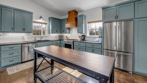 Une cuisine moderne avec des armoires de couleur turquoise, des appareils en acier inoxydable et un îlot central.