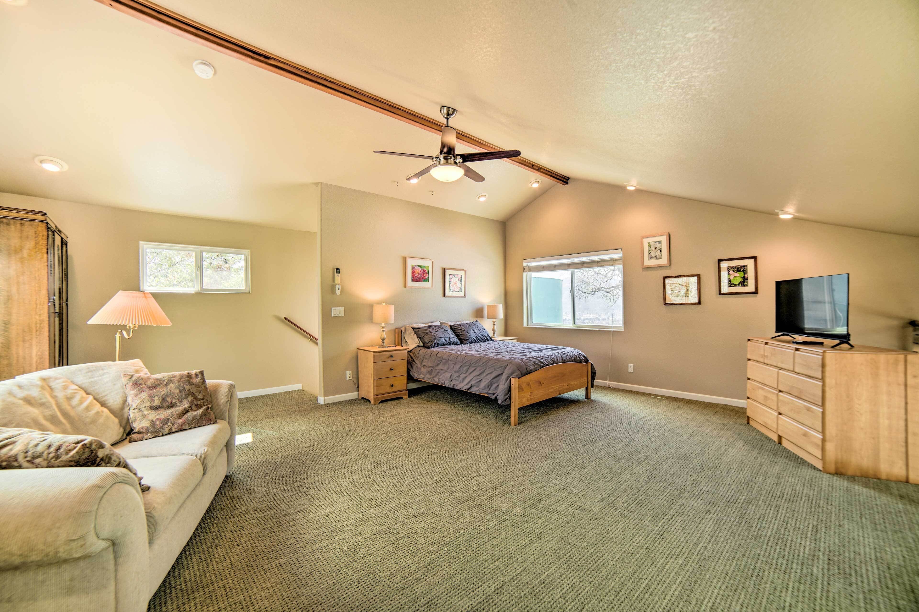 A bedroom with a bed, nightstands, a dresser, a ceiling fan, and a TV.