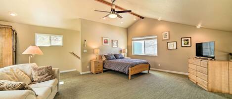 A bedroom with a bed, nightstands, a dresser, a ceiling fan, and a TV.