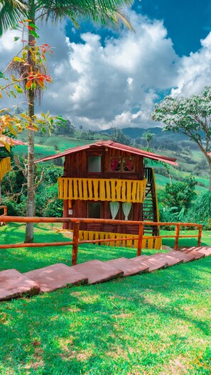 A wooden cabin with a red roof, surrounded by lush greenery and a clear sky. - cabañas monaco (Santa Rosa de Cabal)