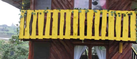 Una cabaña de madera rústica con barandal amarillo y un balcón.