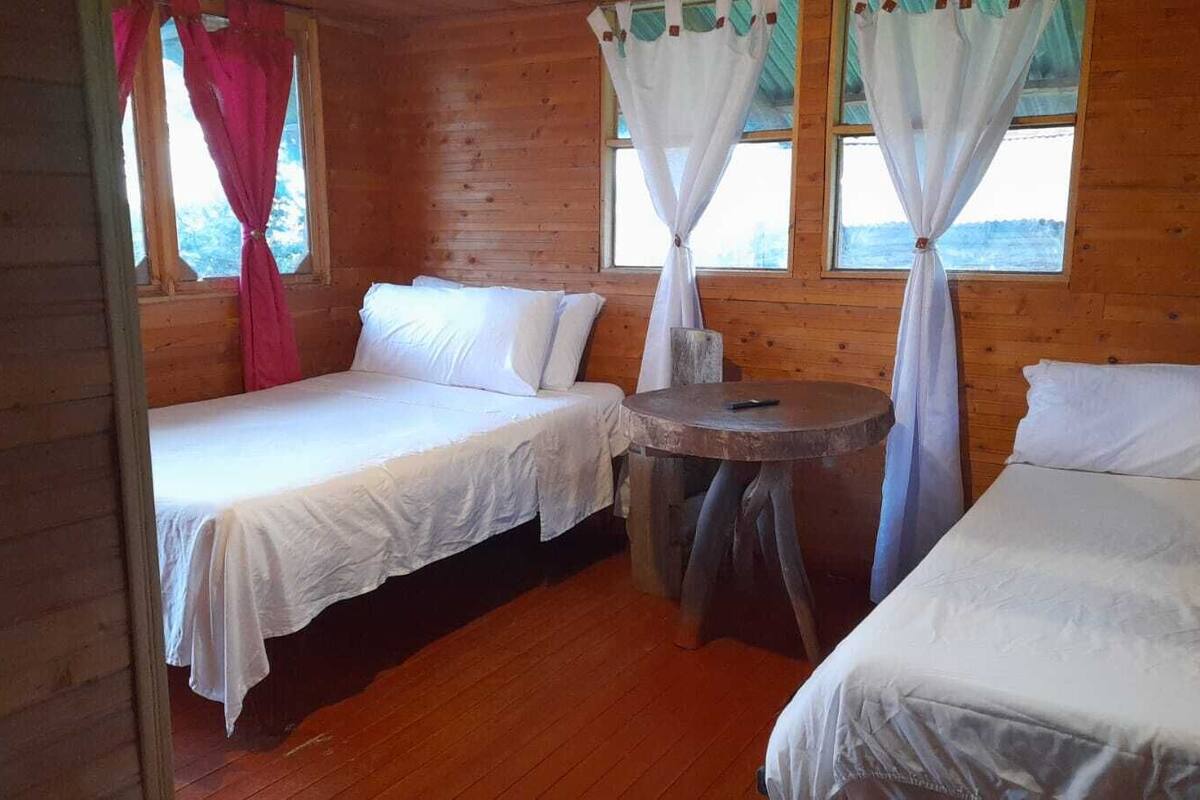 Eine Hütte mit zwei Einzelbetten, einem kleinen runden Tisch und Holzwänden.