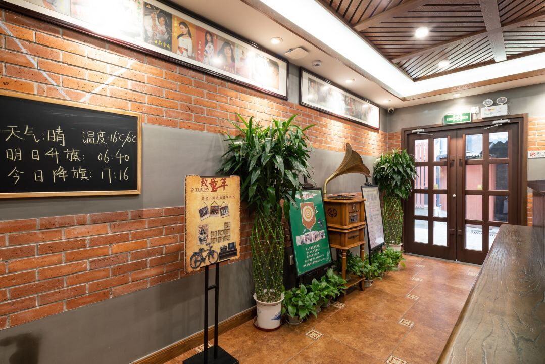 A reception area with a brick wall, a blackboard with information, and potted plants.