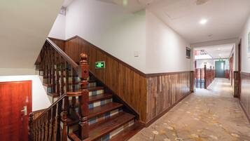 A wooden staircase with a handrail, carpeted floor, and a door on the left.