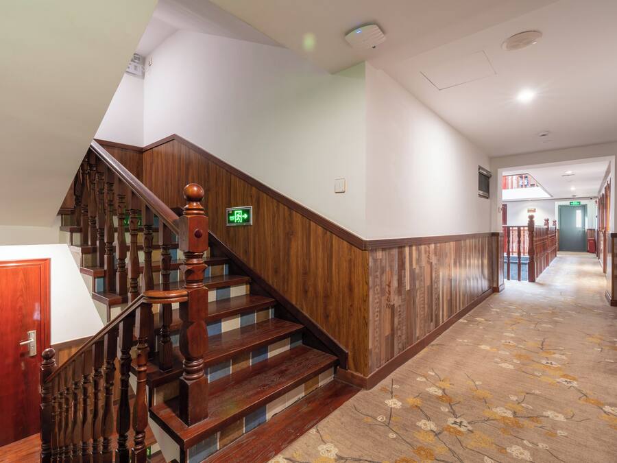 A wooden staircase with a handrail, carpeted floor, and a door on the left.