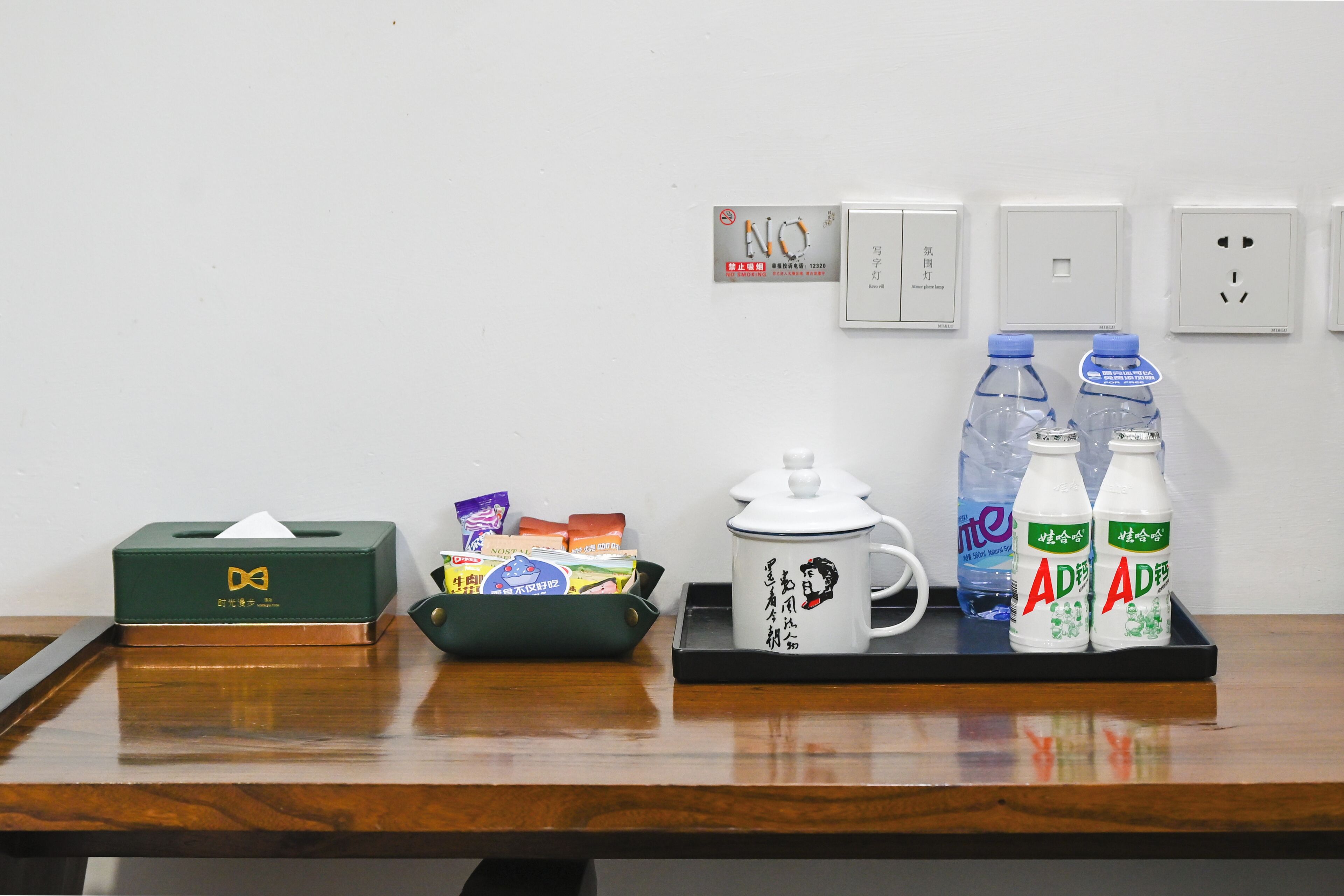 Una mesa de madera con una caja de pañuelos, una taza y dos botellas de agua.