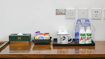 A wooden table with a tissue box, a mug, and two bottles of water.