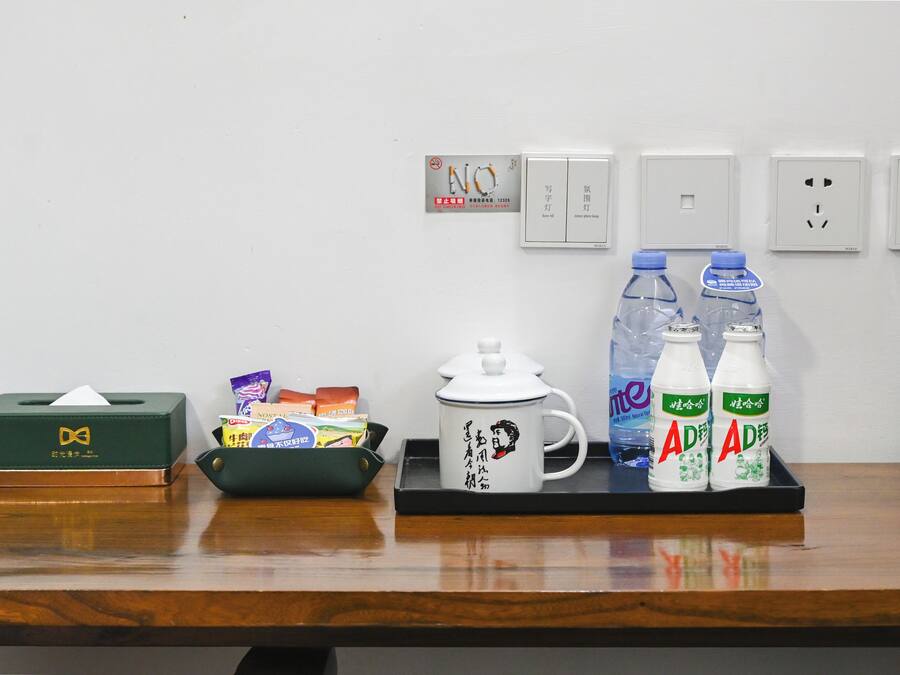 A wooden table with a tissue box, a mug, and two bottles of water.