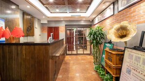 Un área de recepción con un mostrador de madera, una puerta de vidrio que da a una habitación y un altavoz decorativo grande.