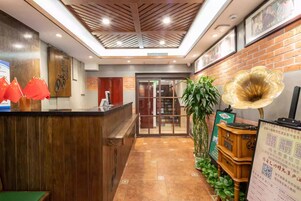 A reception area with a wooden reception desk, a glass door leading to a room, and a large decorative speaker.