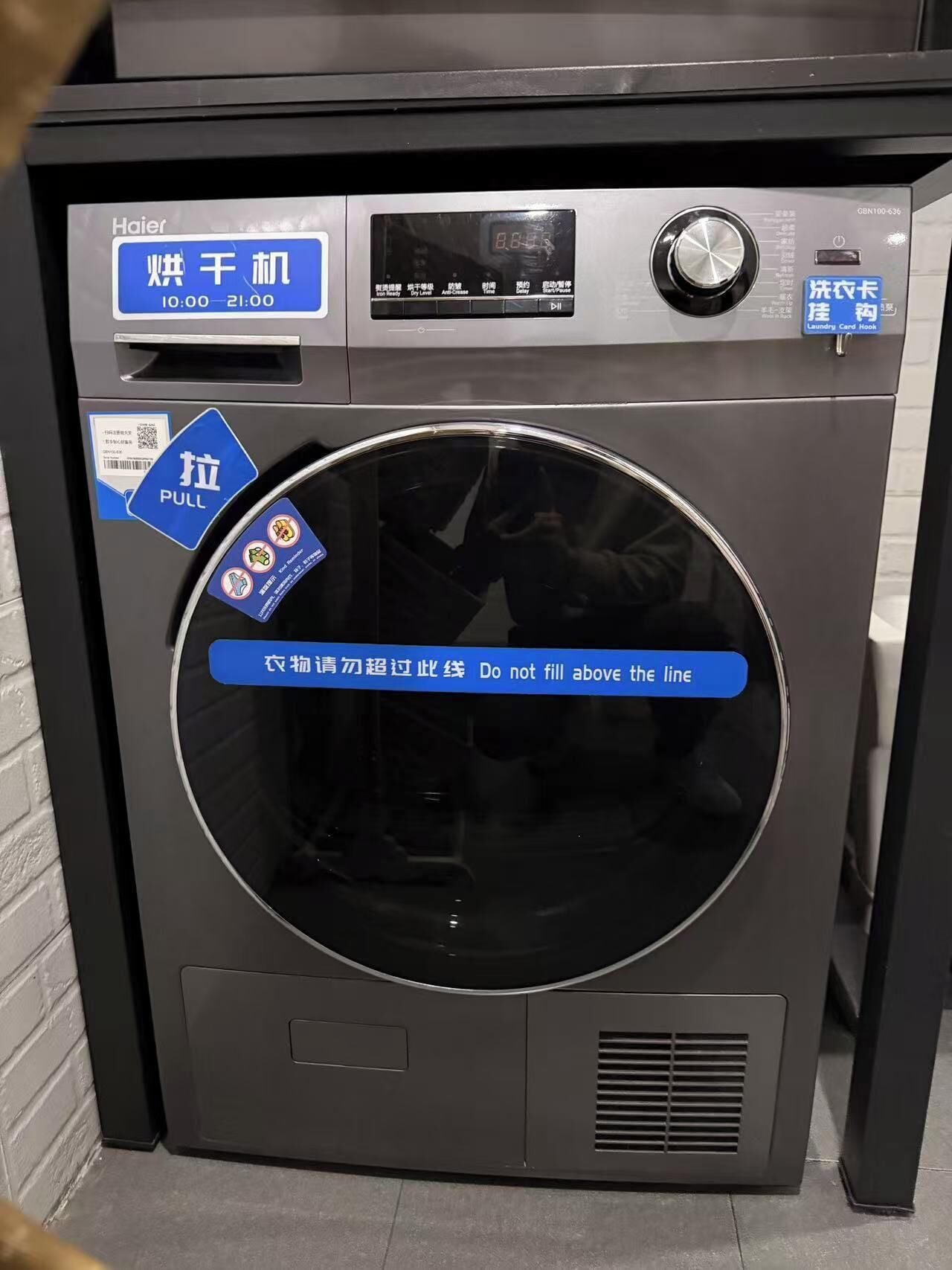 Una lavadora Haier con pantalla digital, panel de control y manual desplegable.