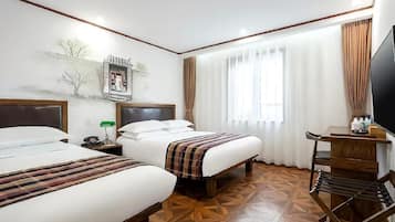 Une chambre d’hôtel avec deux lits, un bureau, une télévision et un sol à motifs.