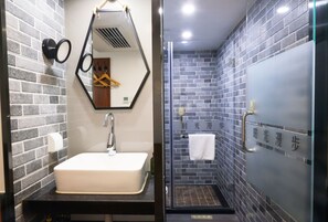 A bathroom with a white sink, a mirror, and a shower area with a glass door. - Nostalgia Hotel（Beijing Tiananmen Square ） (Beijing)