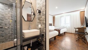 Habitación de hotel con ducha, lavabo, cama y suelo de madera.