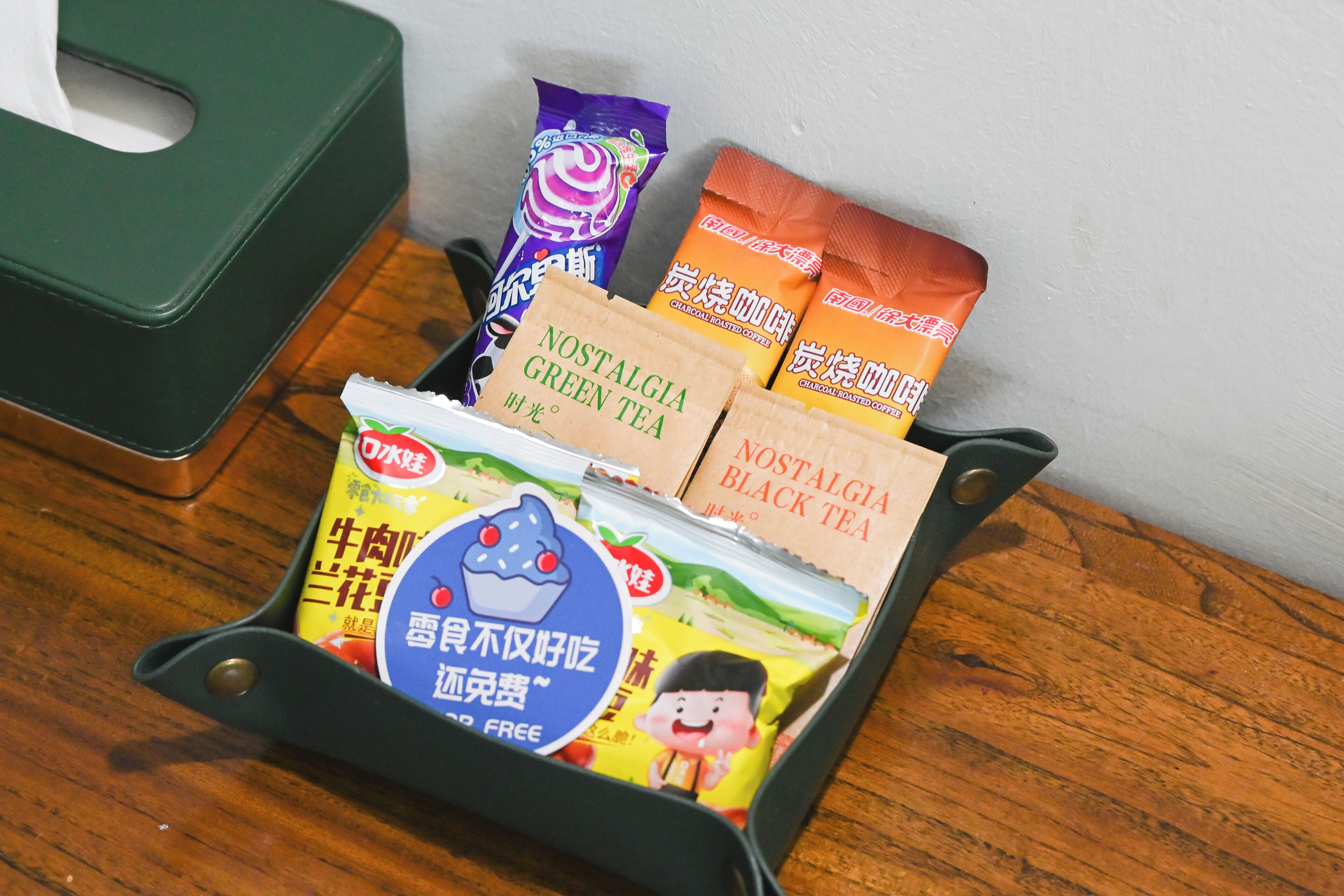 En bakke med forskellige pakker med snacks og drikkevarer, heriblandt Nostalgia Grøn Te og Nostalgia Sort Te.