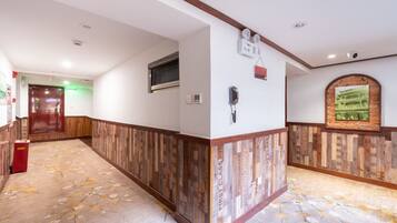 A hotel hallway with wooden paneling, a red fire extinguisher, a wall-mounted phone, and a framed picture.
