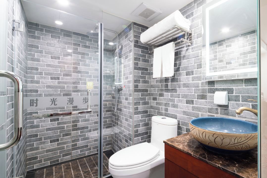 A modern bathroom with a glass shower enclosure, a white toilet, and a blue ceramic sink.