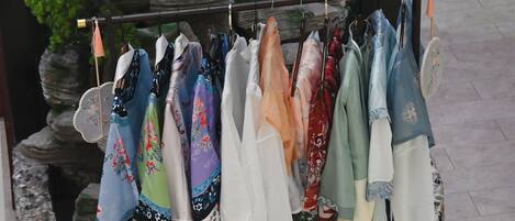 A rack of variously patterned scarves hanging in an outdoor setting with a rocky backdrop.