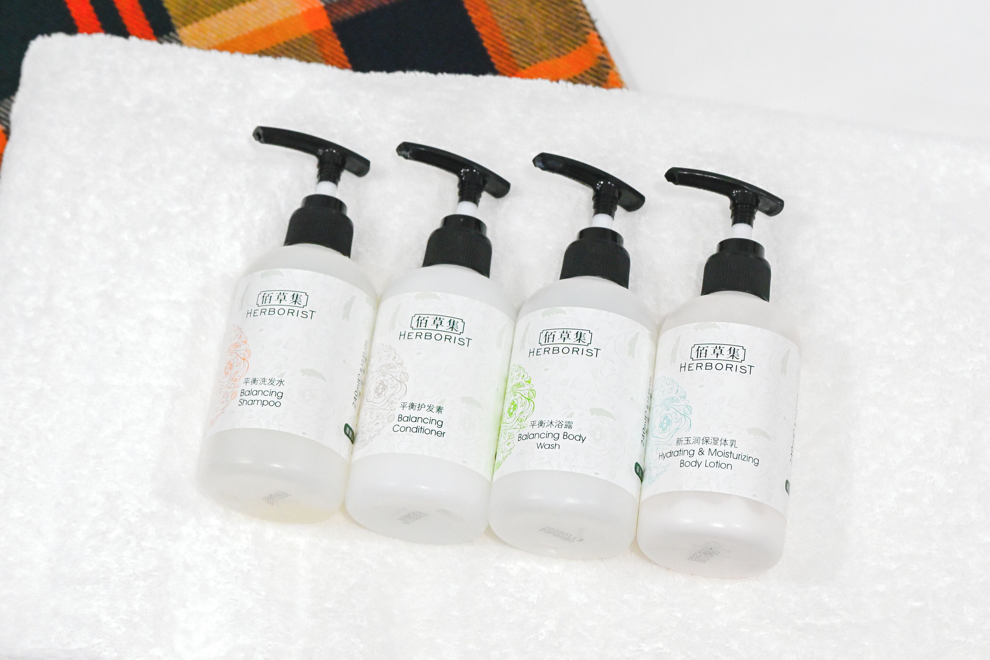 Four bottles of HERBORIST products on a white towel.