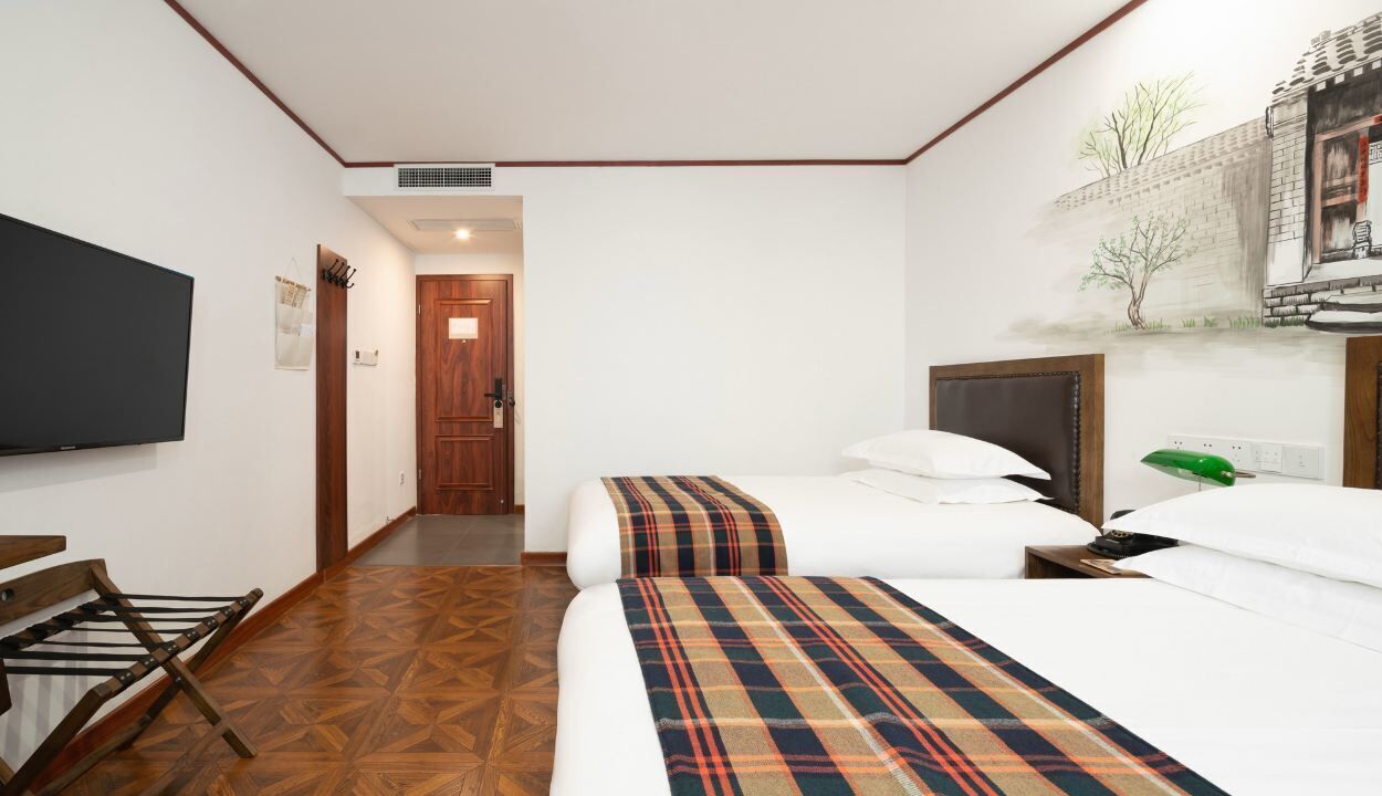 Une chambre d’hôtel avec un lit, une télévision, un plancher en bois et une porte donnant sur une autre pièce.