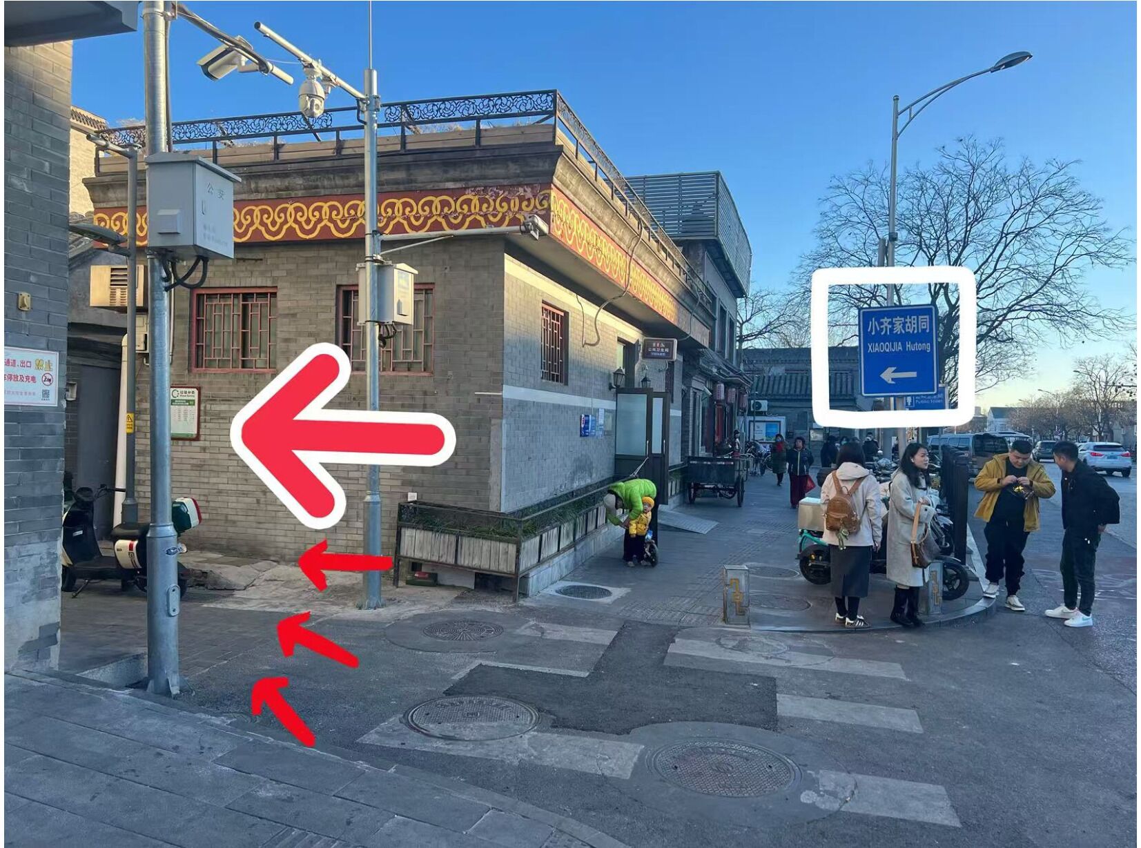 A street scene with a pedestrian crossing, a directional sign, and a building with traditional architecture.