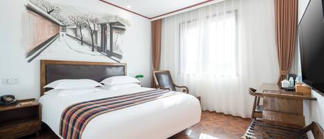 A hotel room with a large bed, a desk with a chair, a television, and a painting on the wall.